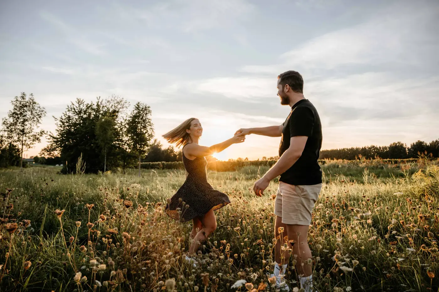 Paar tanzt in der Blumenwiese bei Sonnenuntergang